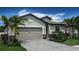 Beautiful home showcasing a paved driveway and lush landscaping under a bright blue sky at 19716 Fishhawk Trl, Venice, FL 34293
