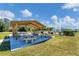 Community area with concrete picnic tables and benches under a wooden awning with view of the pool at 3300 Loveland Blvd # 1504, Punta Gorda, FL 33980