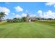 Exterior view of a community putting green and clubhouse with tropical landscaping at 1282 Reserve Dr, Venice, FL 34285