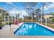 Beautiful screened-in pool area with two red lounge chairs, clear blue water, and stainless steel handrail at 1684 Ruiz St, North Port, FL 34286