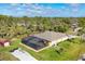 Aerial view of a private home featuring a screened pool, a shed, and a long driveway, surrounded by lush trees at 2737 Cottage Ln, North Port, FL 34286