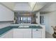 Open kitchen with white cabinets, green countertops, white appliances and view into dining room at 627 Alhambra Rd # 601, Venice, FL 34285