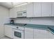 Bright kitchen featuring white cabinets, oven, stovetop, microwave, and views of the rest of the condo at 627 Alhambra Rd # 601, Venice, FL 34285