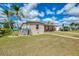 Single-story home with green lawn, mature palm trees, and neutral colored exterior at 6627 Marius Rd, North Port, FL 34287