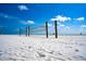 Wide beach scene with volleyball nets in the foreground and beachgoers and distant structures under a blue sky at 110 Vista Hermosa Cir # 102B, Sarasota, FL 34242