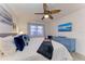 Bright bedroom featuring a ceiling fan, a large window, and a blue dresser with coastal decor at 110 Vista Hermosa Cir # 102B, Sarasota, FL 34242