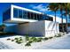 Modern Siesta Beach building with floor-to-ceiling windows and decorative stone against a backdrop of palm trees at 110 Vista Hermosa Cir # 102B, Sarasota, FL 34242