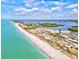 Stunning aerial view captures a long stretch of sandy beach, turquoise water, and charming coastal homes under a bright, cloudy sky at 14724 Ponce De Leon Trl, Port Charlotte, FL 33981