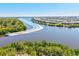 An aerial view captures a boat cruising down a river lined with waterfront homes and lush greenery, offering scenic living at 14724 Ponce De Leon Trl, Port Charlotte, FL 33981