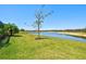 Expansive backyard with lush green grass overlooking a tranquil lake, perfect for outdoor enjoyment at 14724 Ponce De Leon Trl, Port Charlotte, FL 33981