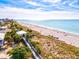 Elevated view of a beach access point with wooden walkway leading to white sand and tranquil blue waters under a partly cloudy sky at 14724 Ponce De Leon Trl, Port Charlotte, FL 33981