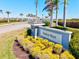 The Harbor West community sign is beautifully landscaped with vibrant yellow flowers and palm trees, welcoming residents and visitors at 14724 Ponce De Leon Trl, Port Charlotte, FL 33981