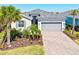 Charming single-Gathering home with a well-manicured lawn, beautiful plants, gray shutters, and a gray brick driveway at 14724 Ponce De Leon Trl, Port Charlotte, FL 33981