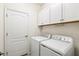 Well-lit laundry room featuring a washer, dryer, and ample storage space with white cabinets at 14724 Ponce De Leon Trl, Port Charlotte, FL 33981