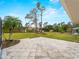 View of backyard with stone paver patio, and view of the lawn, landscaping, and mature trees at 1611 Thomas St, Englewood, FL 34223