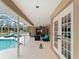 View of screened-in covered patio featuring lounge chairs, outdoor sofas, ceiling fan, and access to pool at 1611 Thomas St, Englewood, FL 34223