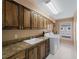 Laundry room features sink, granite countertop, brown cabinets and washer/dryer at 1611 Thomas St, Englewood, FL 34223