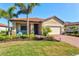 Charming single-story home with a well-manicured lawn, garden, and a brick-paved walkway at 10466 Medjool Dr, Venice, FL 34293