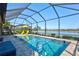 Screened-in pool with a waterfront view, multiple seating areas, a basketball hoop, and lush landscaping at 10466 Medjool Dr, Venice, FL 34293