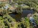 Aerial view of property bordering a pond and surrounded by mature trees in a well-established neighborhood at 1093 Laurel Woods Dr, Nokomis, FL 34275