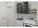 Well-lit laundry room features modern washer and dryer with black cabinets and wooden shelf at 11915 Tempest Harbor Loop, Venice, FL 34292