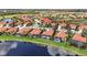 Aerial view of houses with red tile roofs, screened-in pools, and lakes in a golf course community at 133 Treviso Ct, North Venice, FL 34275