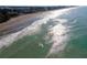 Aerial view of the beach coastline with surfers enjoying the waves and sandy beach at 133 Treviso Ct, North Venice, FL 34275