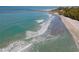 Scenic aerial view of the beach with surfers and the turquoise ocean at 133 Treviso Ct, North Venice, FL 34275
