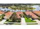 Aerial view of homes with red tile roofs, lush landscaping, and a scenic lake with island at 133 Treviso Ct, North Venice, FL 34275