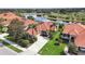 Aerial view of homes with red tile roofs, tropical landscaping, and a scenic lake at 133 Treviso Ct, North Venice, FL 34275