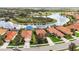 Aerial view of homes with red tile roofs, lush landscaping, and a scenic lake with island at 133 Treviso Ct, North Venice, FL 34275