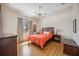Bright bedroom with wood floors, ceiling fan, window with curtains, and ensuite bathroom at 133 Treviso Ct, North Venice, FL 34275