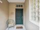 Welcoming front entrance featuring a teal door, glass block window and a cozy wicker chair at 133 Treviso Ct, North Venice, FL 34275