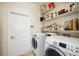 Bright laundry room featuring white washer and dryer, white door, and wire shelving for storage at 133 Treviso Ct, North Venice, FL 34275