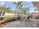 Screened patio featuring a dining table, grill, and views of the manicured backyard with lush landscaping at 1537 Monarch Dr, Venice, FL 34293