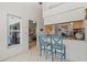 Bright kitchen featuring white tile floors, a breakfast bar with seating, and an open view to the living room at 174 Southampton S Pl # 345, Venice, FL 34293