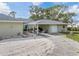 Back exterior view of house with ample driveway space and covered patio area, great for outdoor entertainment at 1800 Whispering Pines Cir, Englewood, FL 34223