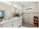 Elegant bathroom featuring a double sink vanity, a glass-enclosed shower with decorative tiles, and neutral decor at 19832 Bridgetown Loop, Venice, FL 34293