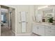 Well-lit bathroom with a white vanity, ample storage, and a glimpse of a serene bedroom through an open doorway at 19832 Bridgetown Loop, Venice, FL 34293
