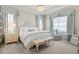 Serene main bedroom with a tray ceiling, elegant chandelier, and beautiful blue and white patterned curtains at 19832 Bridgetown Loop, Venice, FL 34293