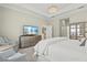 Bright and spacious main bedroom featuring a comfortable sitting area, stylish dresser, and a large television at 19832 Bridgetown Loop, Venice, FL 34293