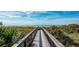 Picturesque view of a wooden boardwalk leading to a serene beach with clear blue waters and lush vegetation at 19836 Bridgetown Loop, Venice, FL 34293