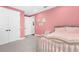 Pink bedroom featuring a cozy bed with soft blankets and pillows, complemented by light gray carpet at 19836 Bridgetown Loop, Venice, FL 34293