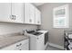 Well-equipped laundry room with modern washer and dryer, ample cabinetry, and granite countertops at 19836 Bridgetown Loop, Venice, FL 34293