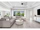 Open-concept living room with coffered ceiling, large sectional sofa, and wood-look tile floors at 19836 Bridgetown Loop, Venice, FL 34293