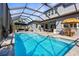 Screened pool with lounge chairs and dining table featuring an umbrella and outdoor kitchen at 19836 Bridgetown Loop, Venice, FL 34293