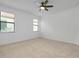 A bright bedroom with neutral carpet features a ceiling fan and windows for natural light at 24229 Spartina Dr, Venice, FL 34293