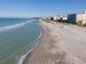 Expansive beach view with light blue ocean waves and beachfront condos on a clear day at 407 Rubens Dr, Nokomis, FL 34275