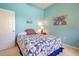 Bedroom with a blue wall, quilt-covered bed, and a vintage style circus poster at 408 Otter Creek Dr, Venice, FL 34292