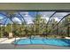 Outdoor pool with sparkling blue water, screened enclosure, and tropical landscaping beyond at 408 Otter Creek Dr, Venice, FL 34292